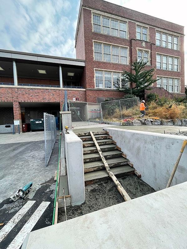 fresh concrete poured for exterior stairs in front of a brick building