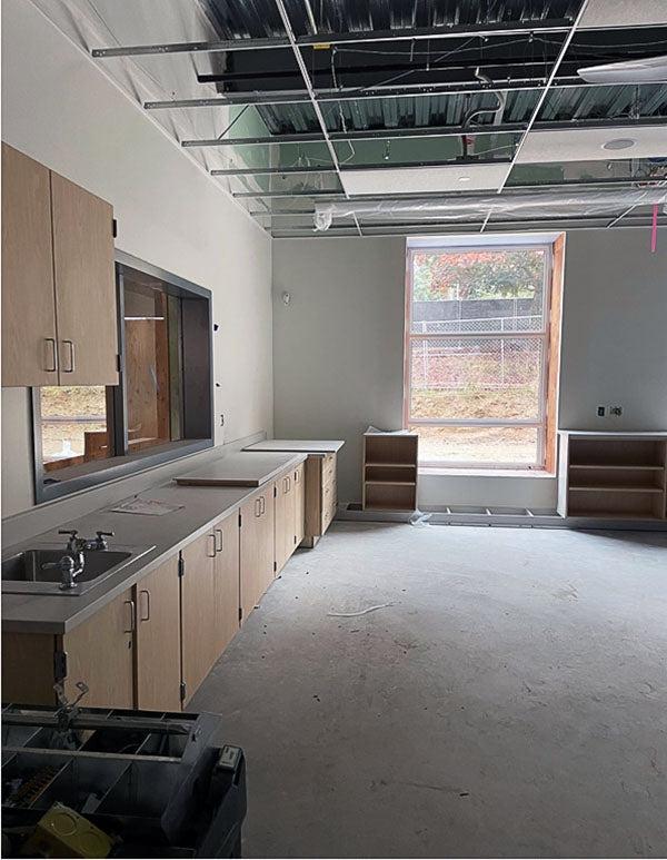 an unfinished room has cabinets and a ceiling grid