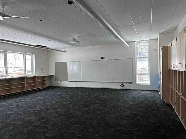a classroom with cabinets, carpet, and a white board -- no furniture