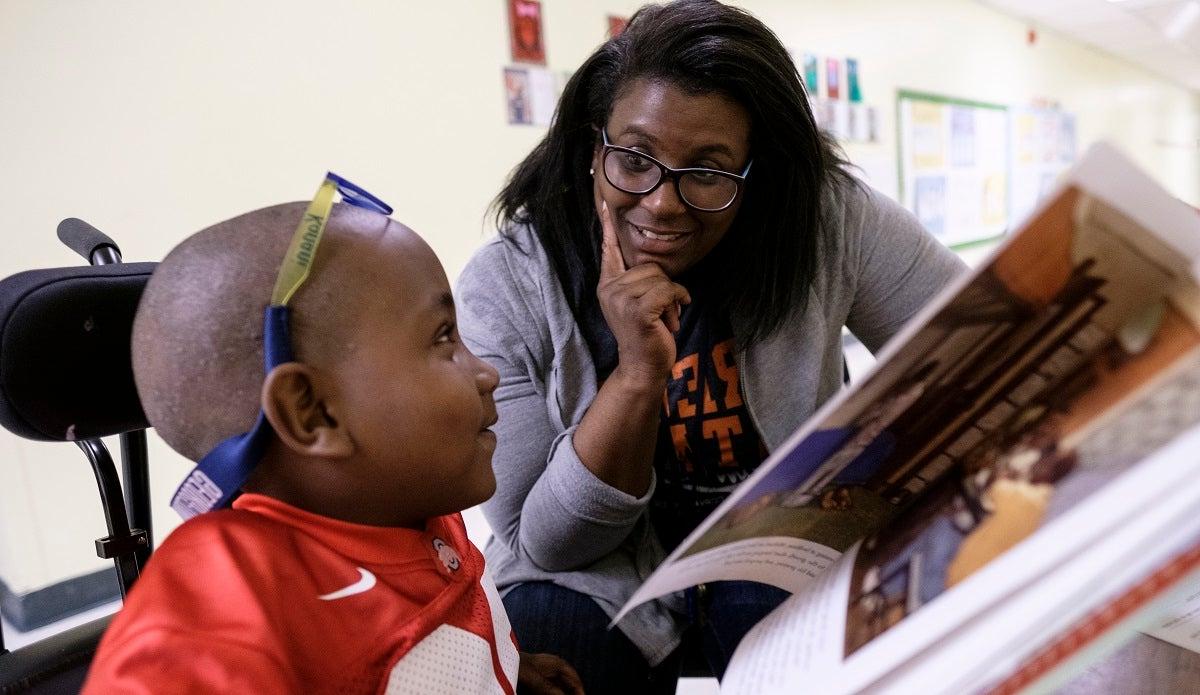 一个教育工作者和一个年轻的学生在教室里一边看书一边交谈.
