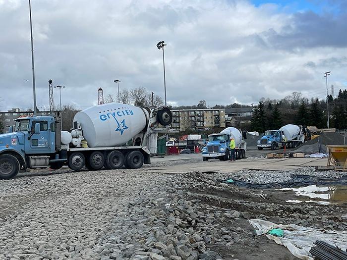 concrete mixer trucks lined up on a drive way among mud puddles