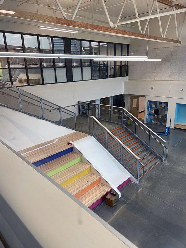 looking down into a large space with a stairway for walking, a stairway for sitting, and a slide