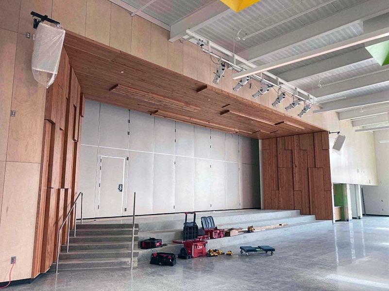 Proscenium surrounding a stage is made of wood. the stage and steps leading to it are concrete